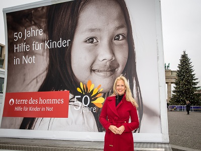 Barbara Schöneberger vor Plakat von terre des hommes