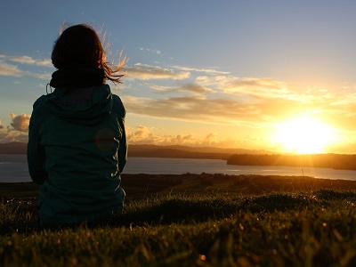 Dame sitzt vor Sonnenuntergang