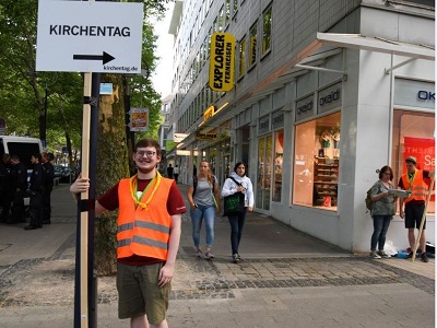 Ein Helfer des Kirchentags mit einem Wegweiser in der Dortmunder Innenstadt