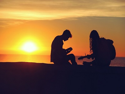 Zwei Musiker spielen Gitarre beim Sonnenuntergang