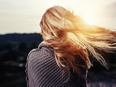 Rueckenansicht von Frau mit wehenden Haaren