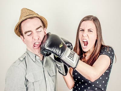 Mann gibt Frau mit Boxhandschuhen einen Kinnhaken
