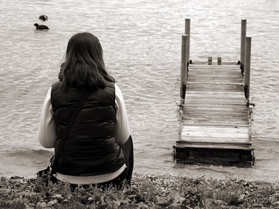 Frau sitzt am See